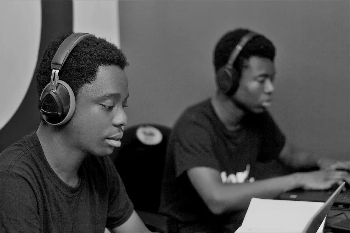 Two team members wearing headphones, working side by side at their laptops.